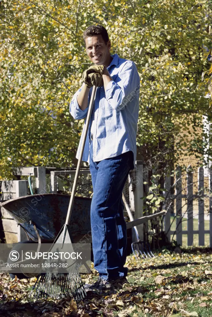 Portrait of a mid adult man standing with a rake