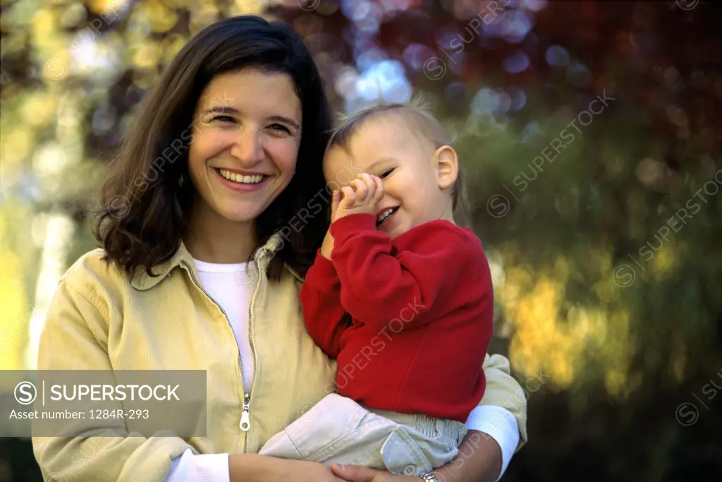 Portrait of a mother holding her baby boy in a park smiling