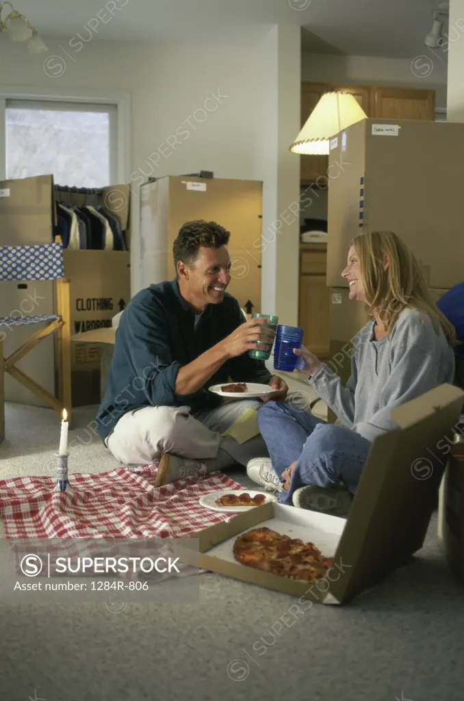 Young couple toasting sitting on the floor