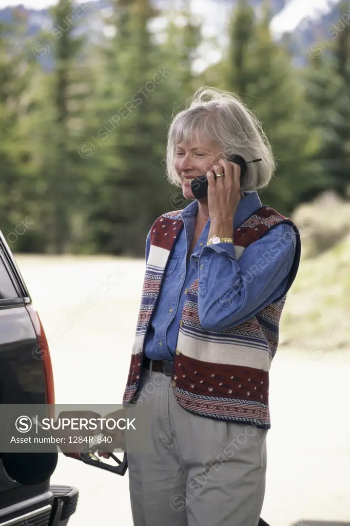 Senior woman talking on a mobile phone at a gas station