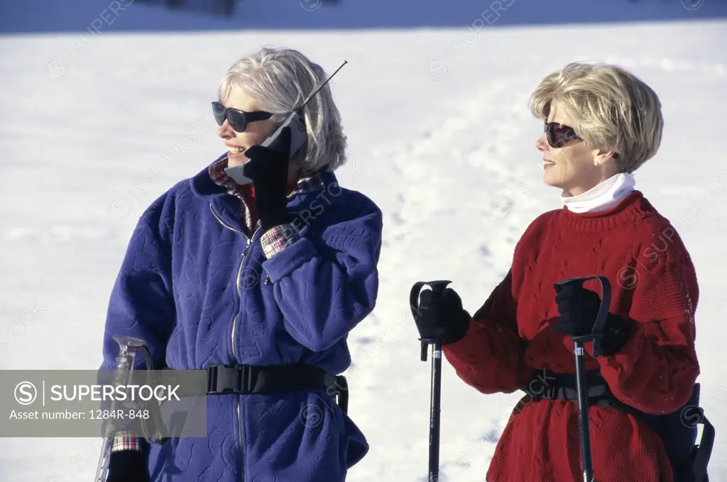 Woman talking on a mobile phone with a woman standing beside her