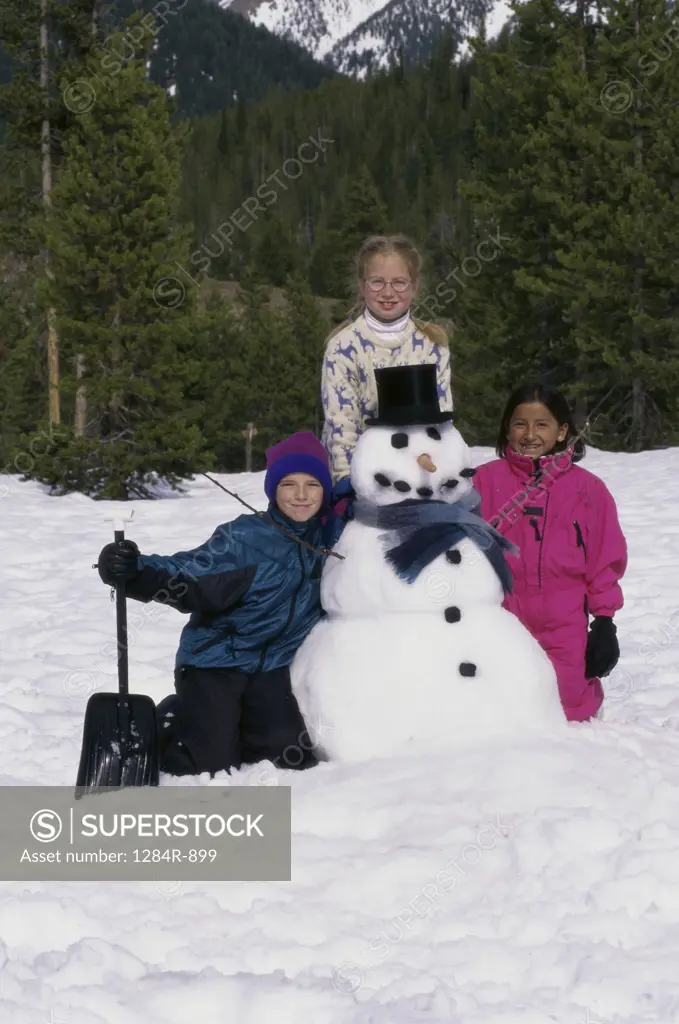 Portrait of two girls and a boy with a snowman