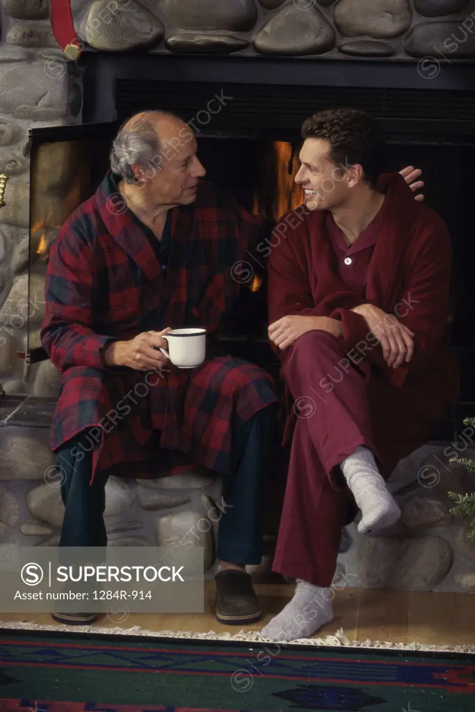 Father and son sitting near a fireplace talking