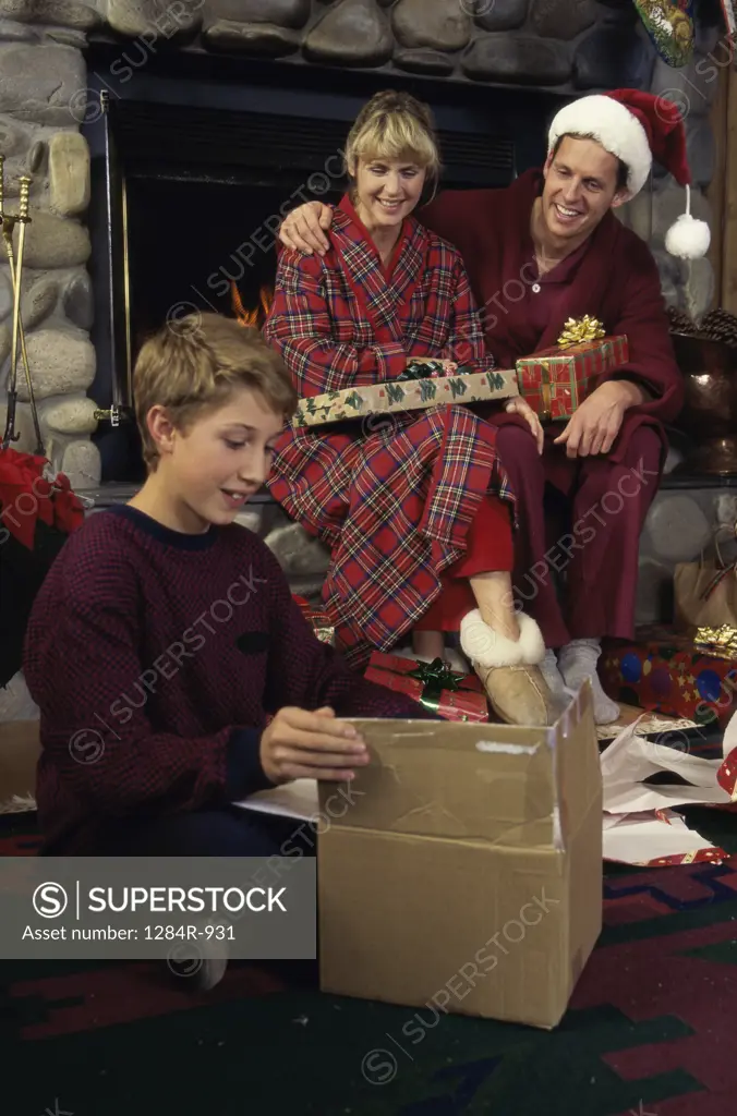 Son opening a gift while his parents watch