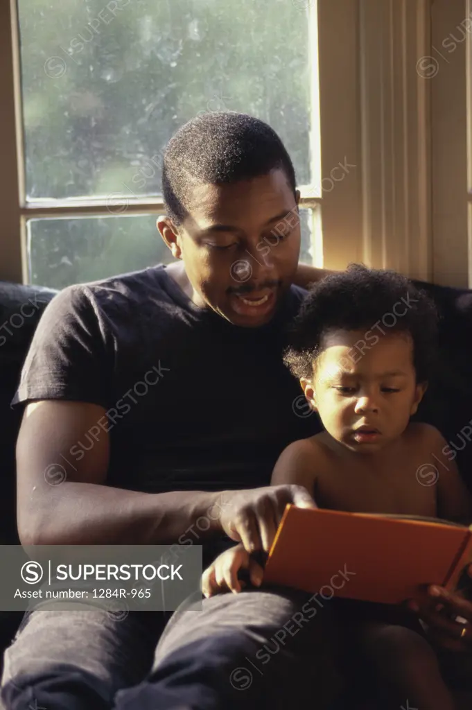 Father helping his son read a book