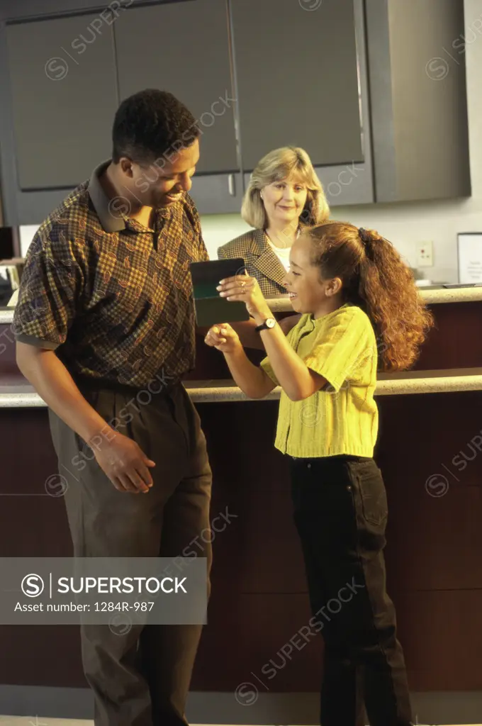 Father and daughter banking with a female teller