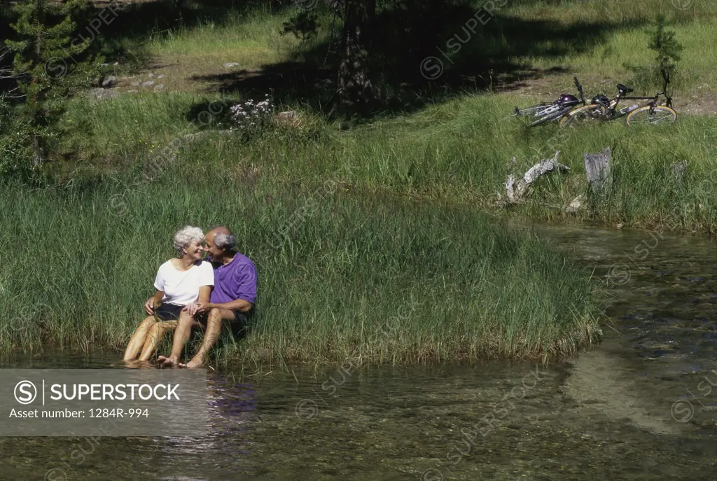 Senior couple sitting on a riverbank