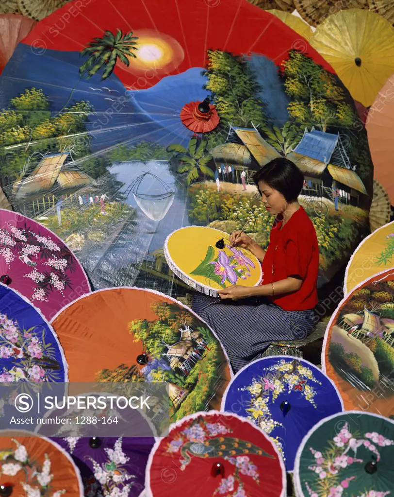 Side profile of a young woman painting a parasol, Chiang Mai Province, Thailand