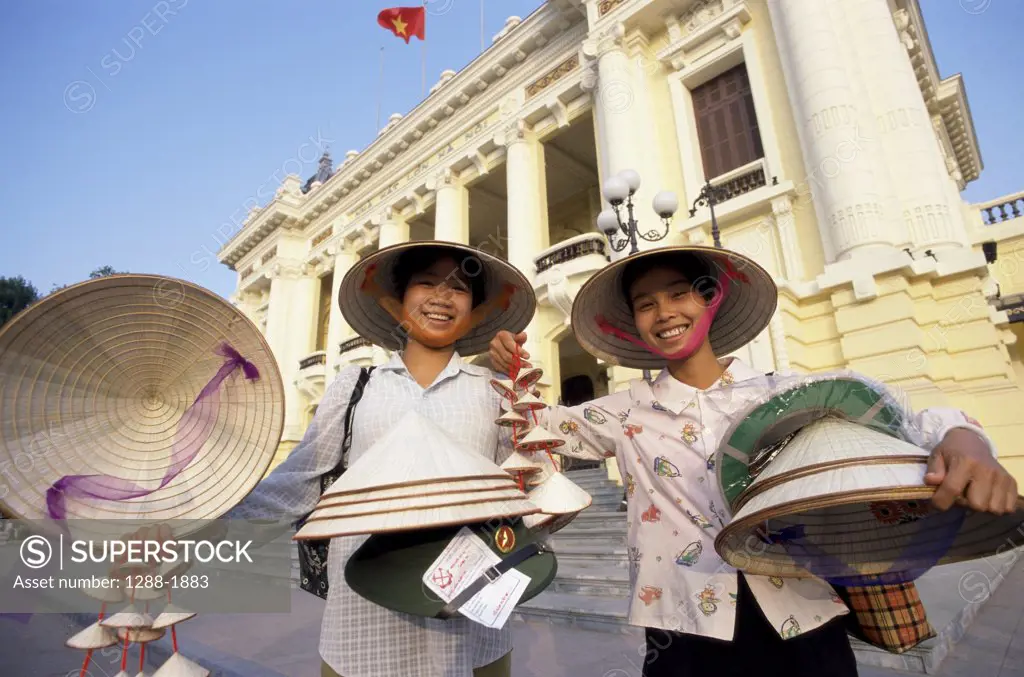 Low angle view of two women selling hats in Hanoi, Vietnam