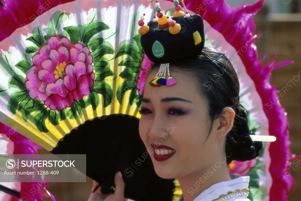 Close-up of a young woman holding a folding fan and dressed in traditional clothing, South Korea