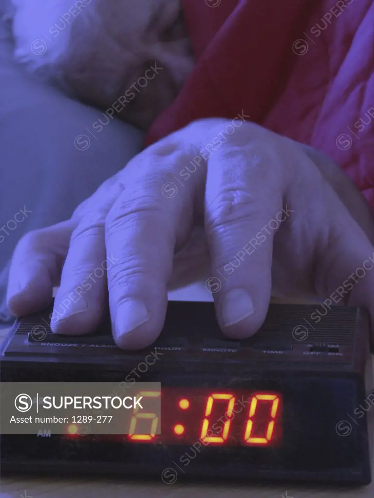 Close-up of a man's hand reaching for the alarm clock
