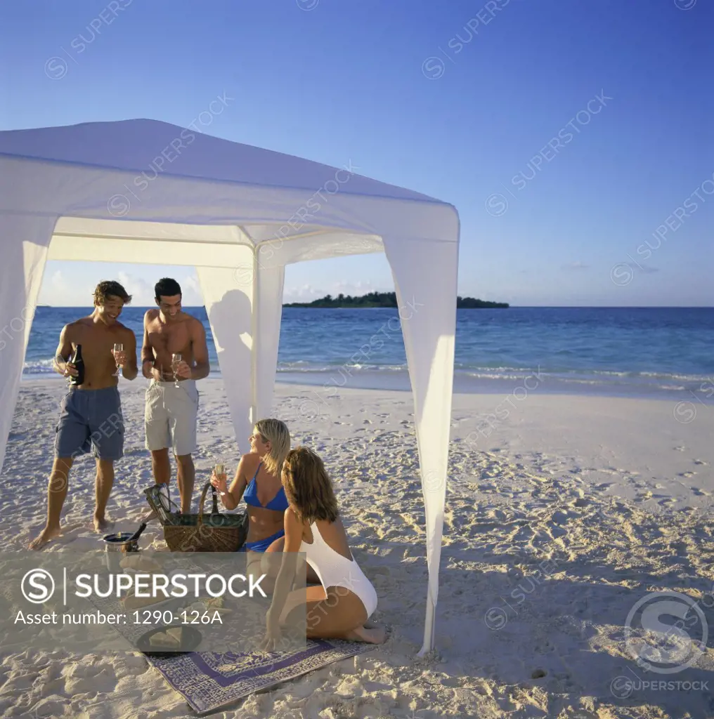 Two young couples under a tent on the beach