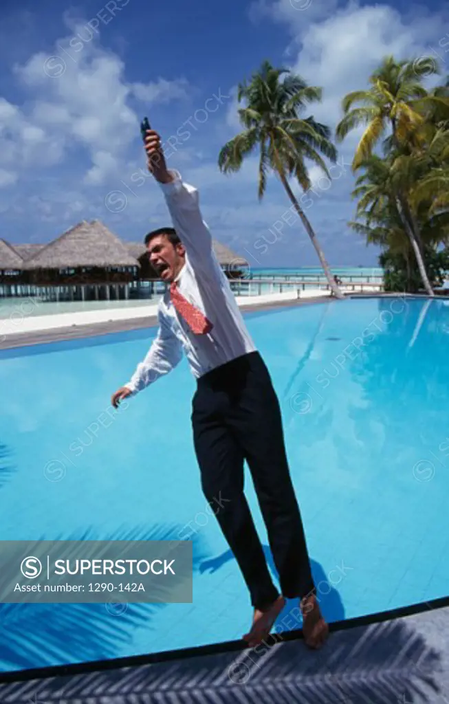 Businessman falling in a swimming pool with a mobile phone