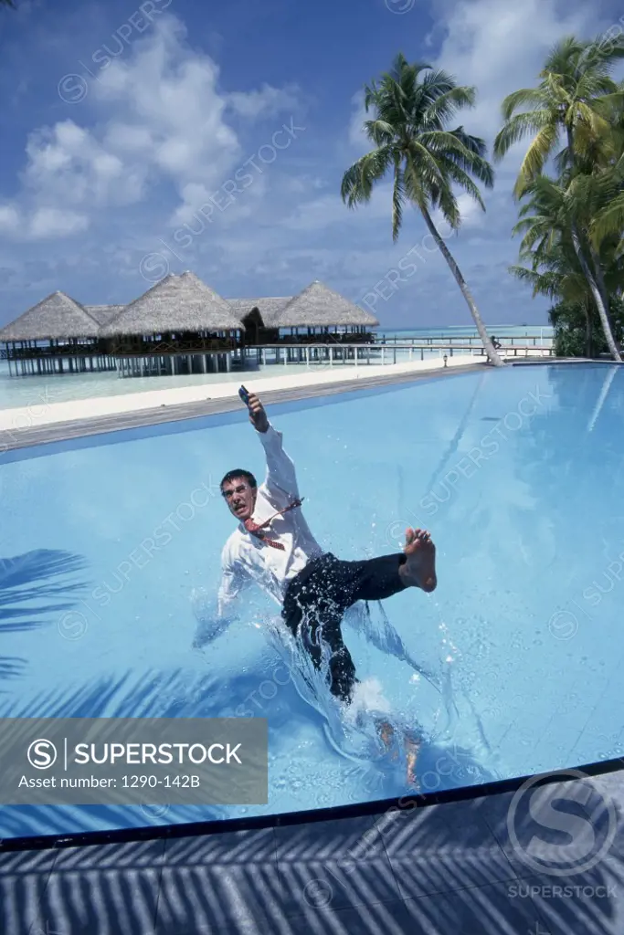 Businessman falling in a swimming pool with a mobile phone