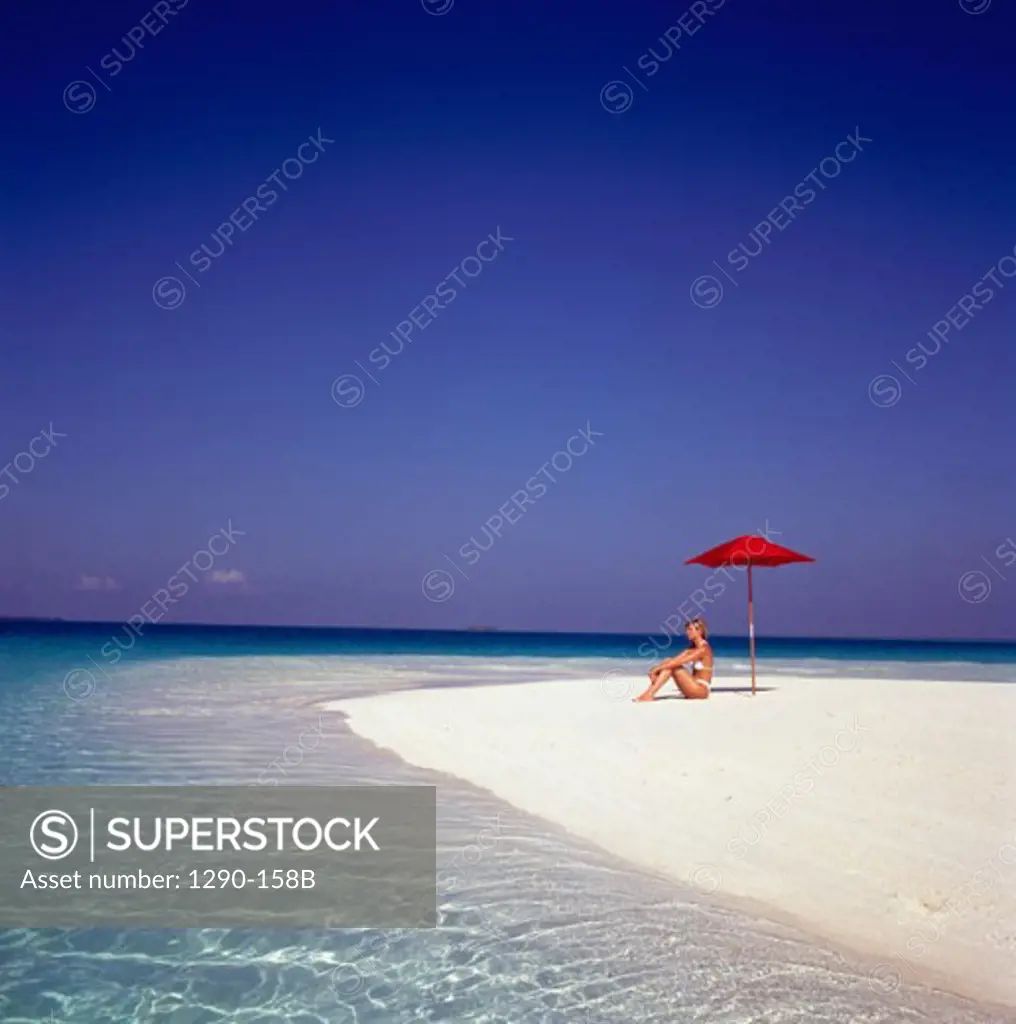Side profile of a young woman sitting on the beach, Maldives