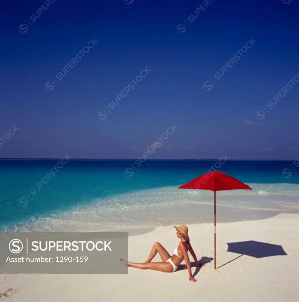 Side profile of a young woman reclining on the beach