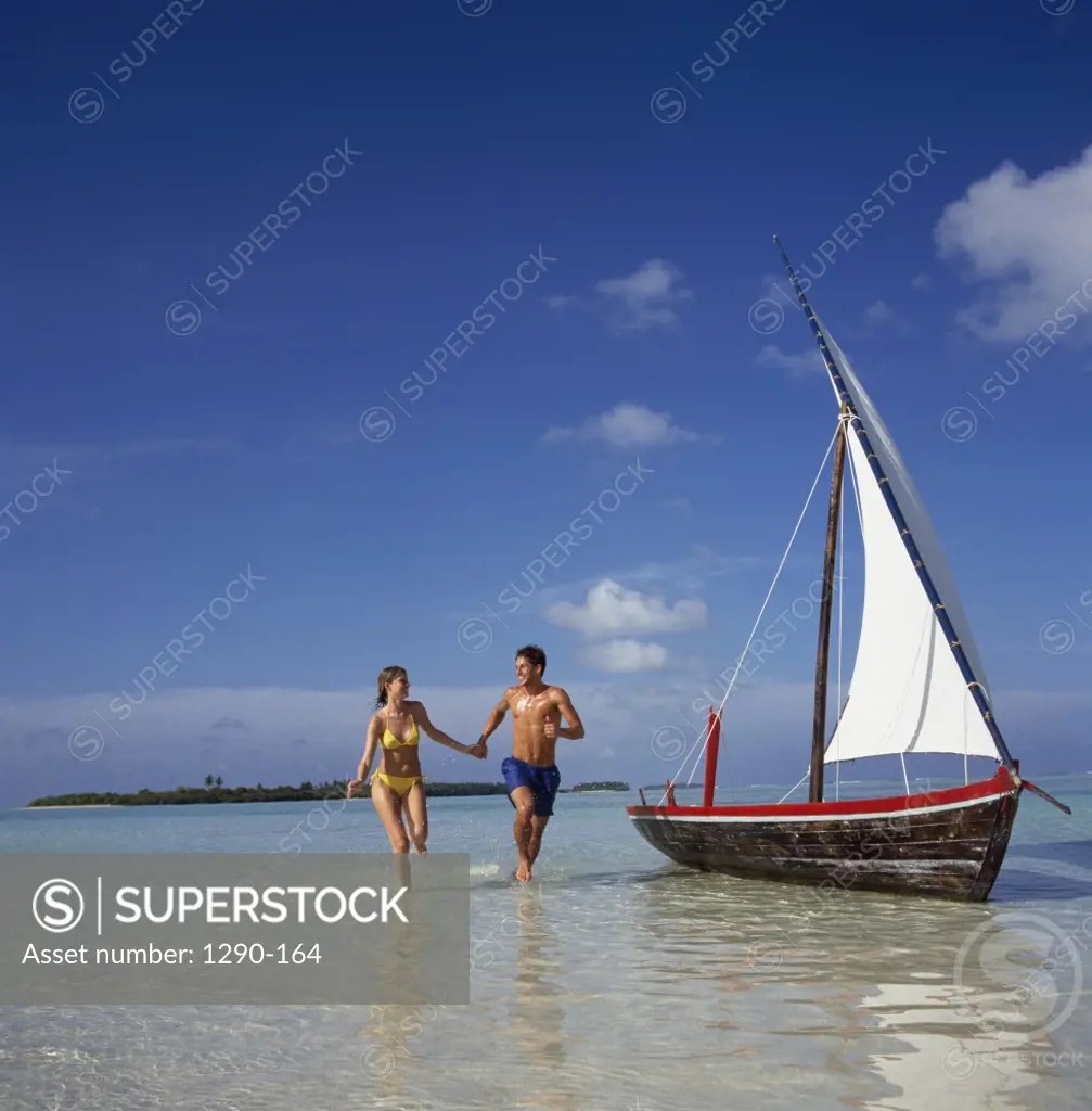 Young couple running in water on the beach