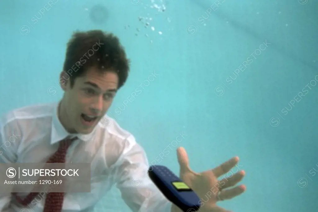 Close-up of a businessman catching a mobile phone underwater