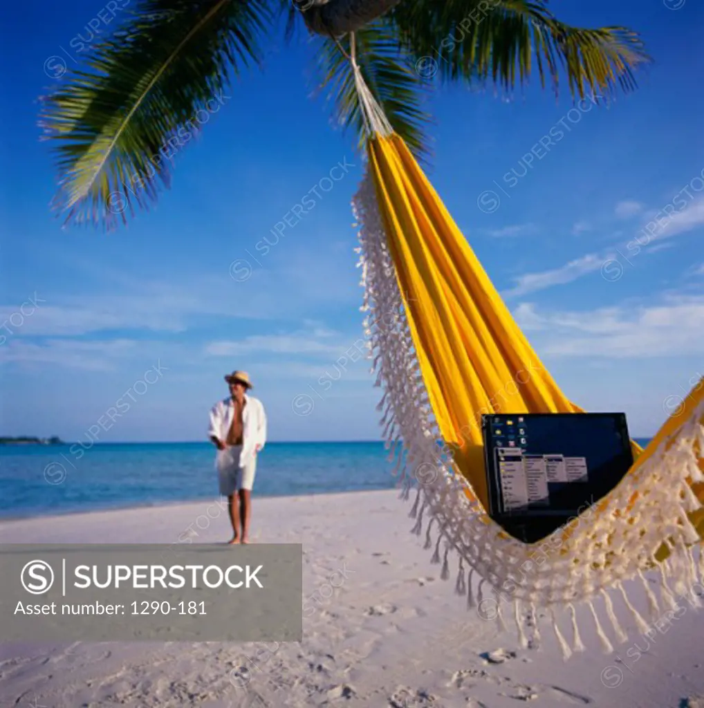 Laptop in a hammock with a businessman walking on the beach in the background