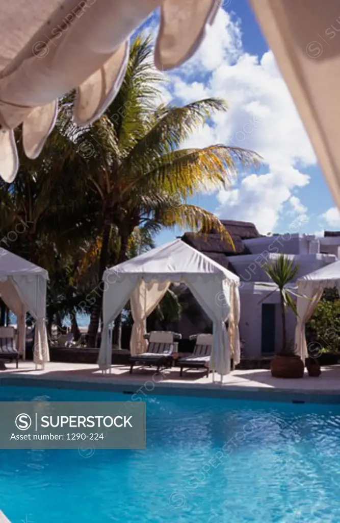 Lounge chairs under cabanas at poolside