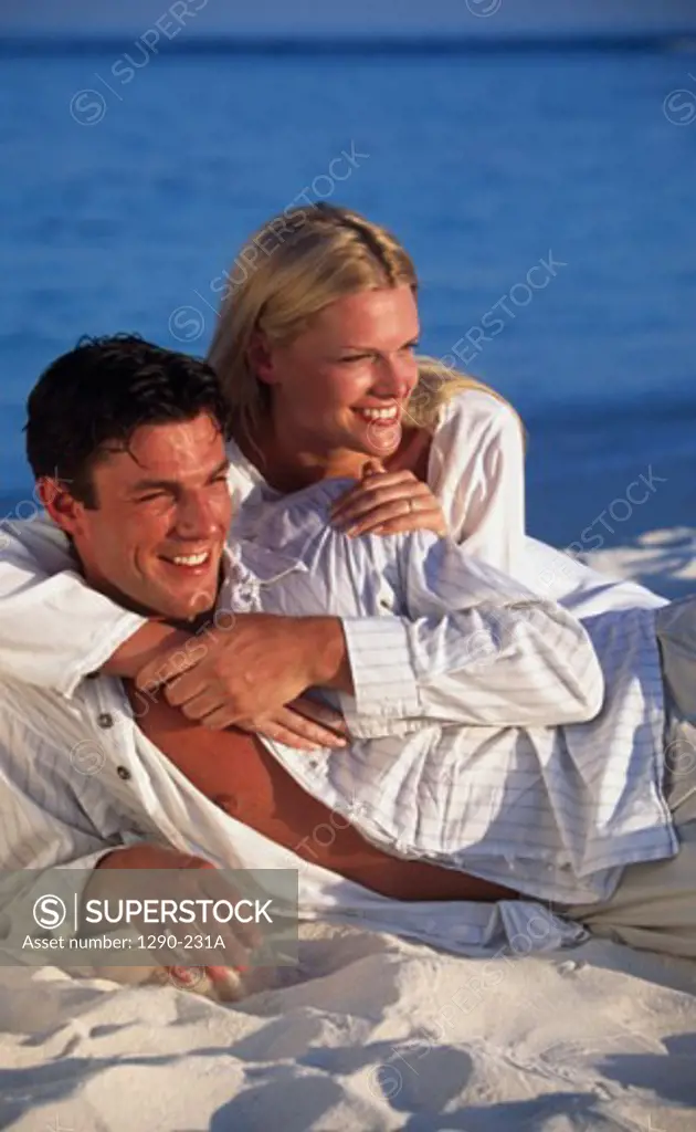 Young woman embracing a young man from behind on the beach
