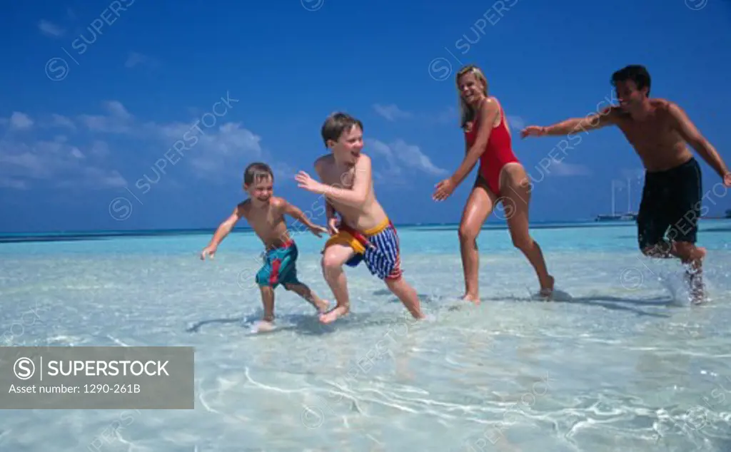Young couple with their two sons running on the beach