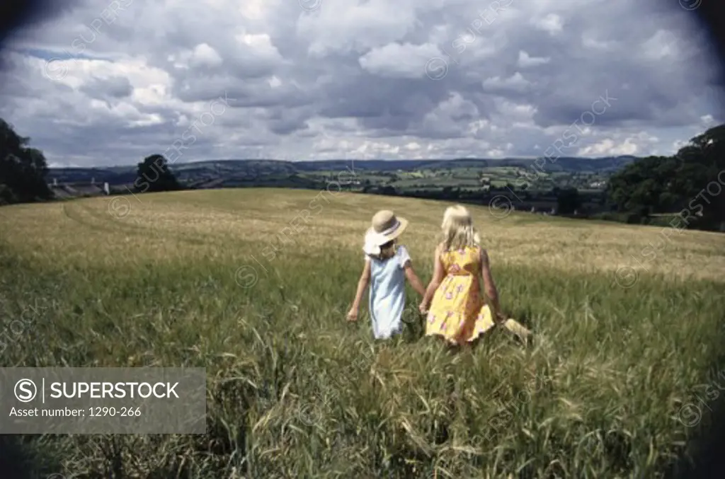 Rear view of two girls strolling in a field