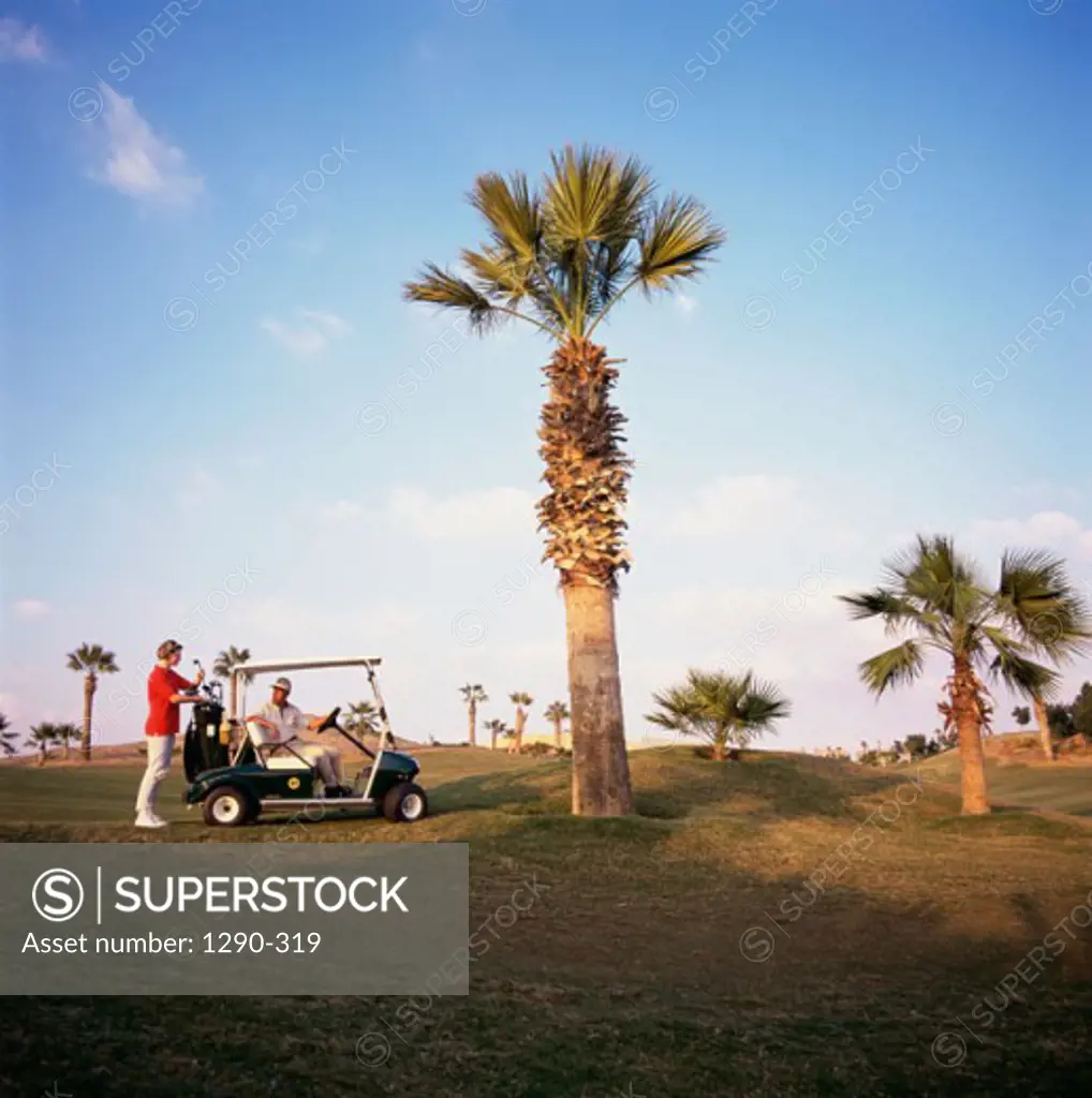 Man sitting on a golf cart with a woman standing behind him, Sharm el Sheikh, Egypt