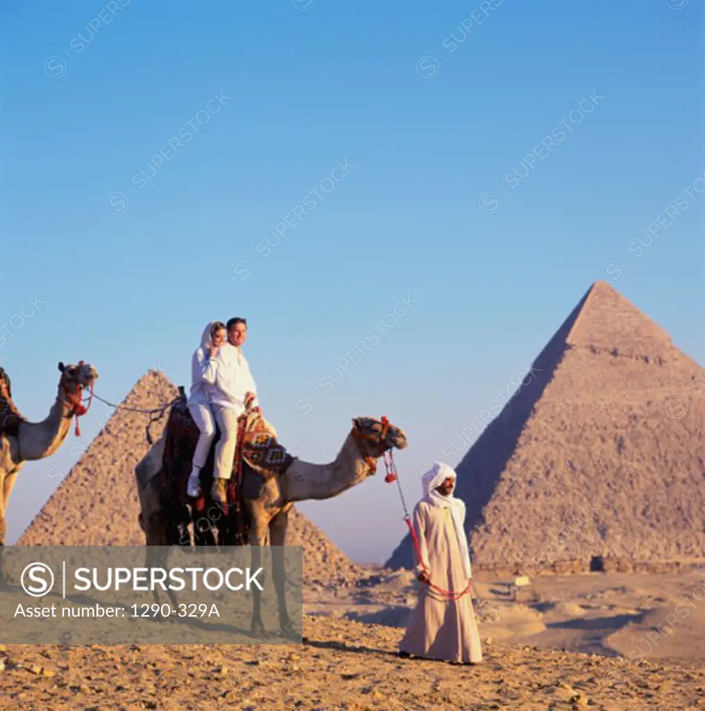 Young couple riding a camel lead by a Bedouin man, Giza, Egypt