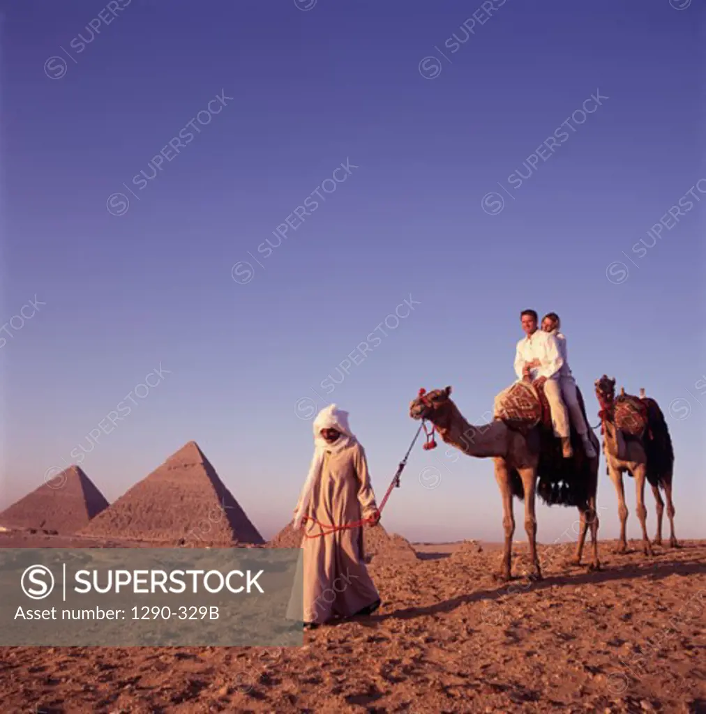 Young couple riding a camel lead by a Bedouin man, Giza, Egypt