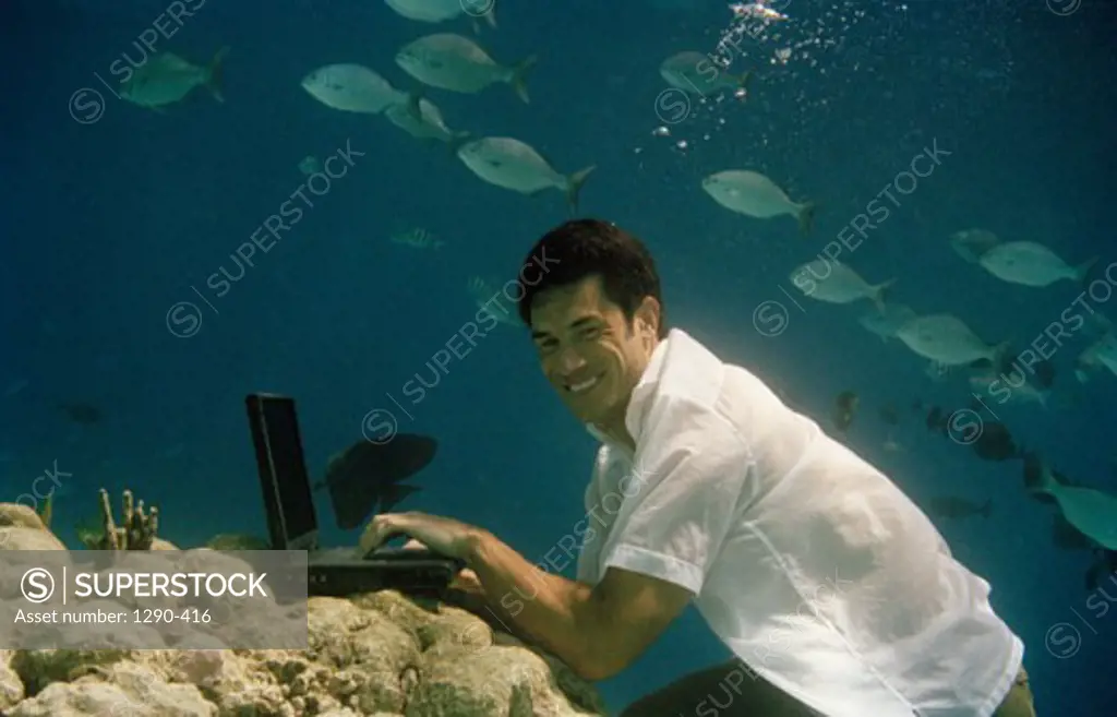 Side profile of a young man using a laptop underwater