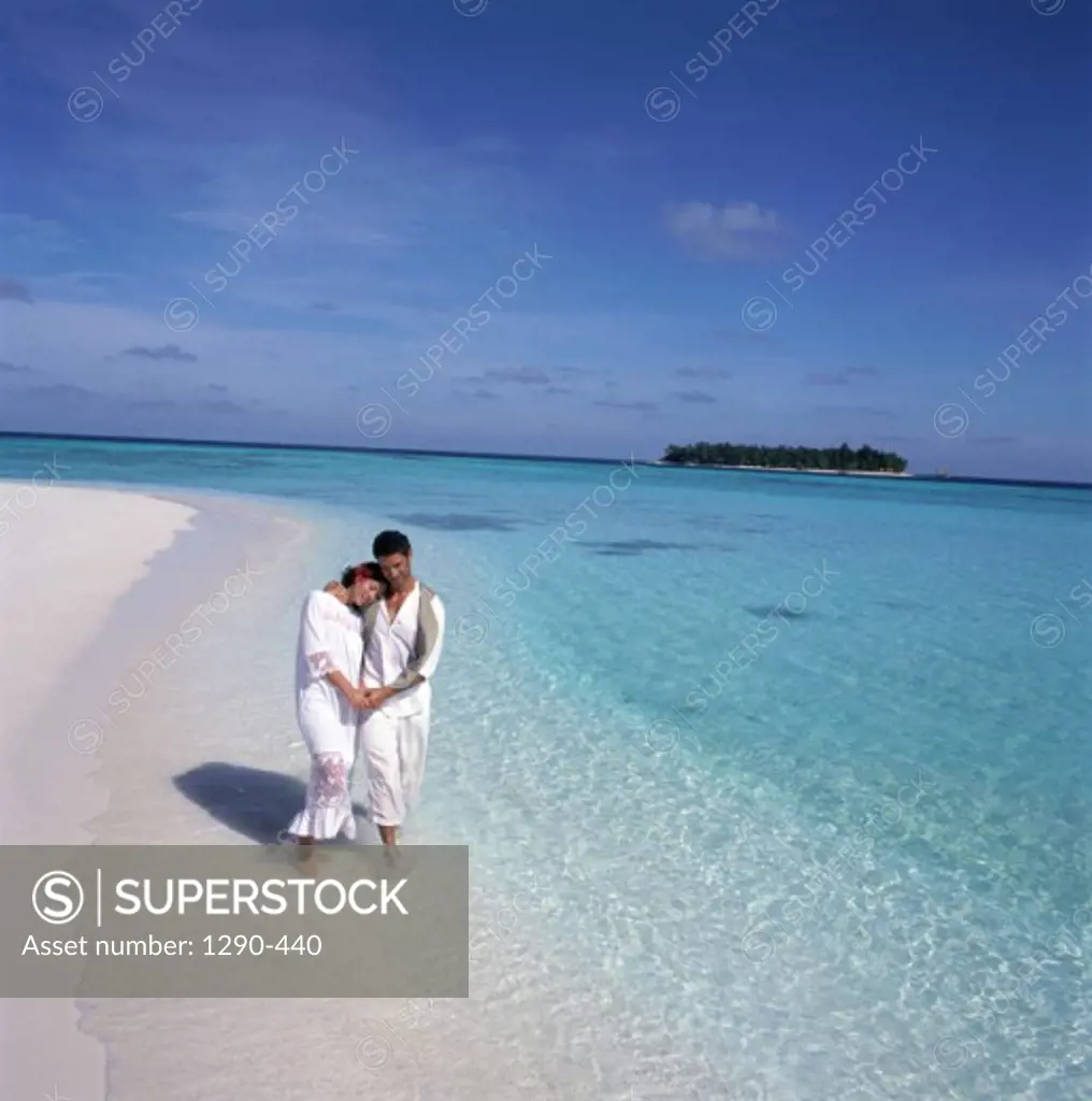 Young couple wading in water on the beach, Maldives