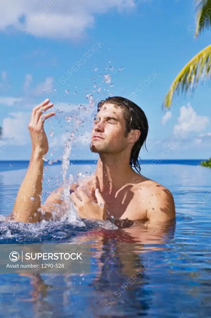 Young man splashing water with his hands, Banyan Tree Hotel, Anse Intendance, Mahe Island, Seychelles