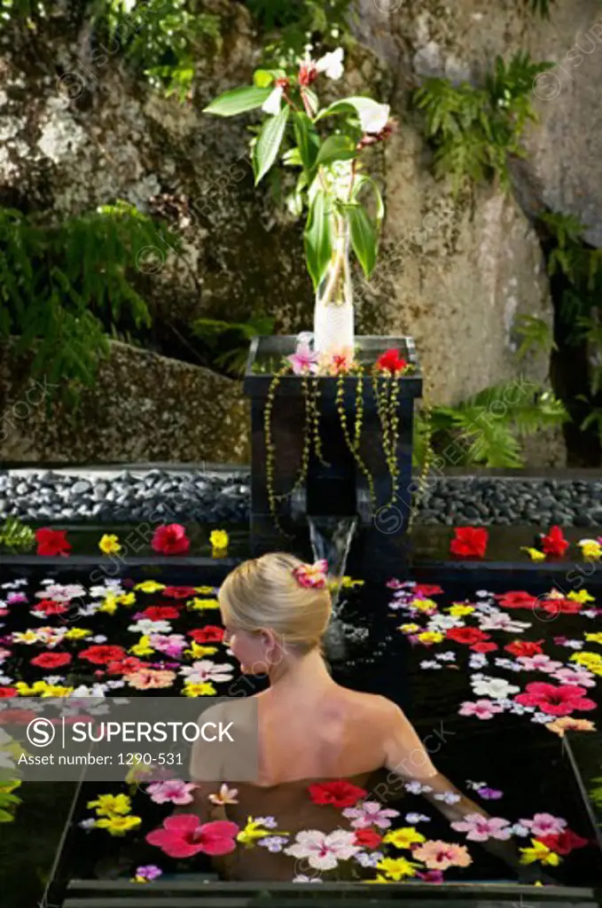 Rear view of a young woman using aromatherapy in a swimming pool, Banyan Tree Hotel, Anse Intendance, Mahe Island, Seychelles