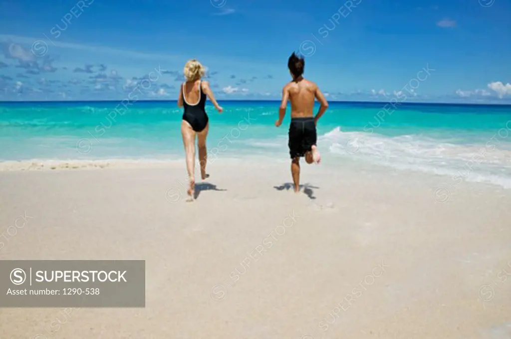 Rear view of a young couple running on the beach, Mahe Island, Seychelles