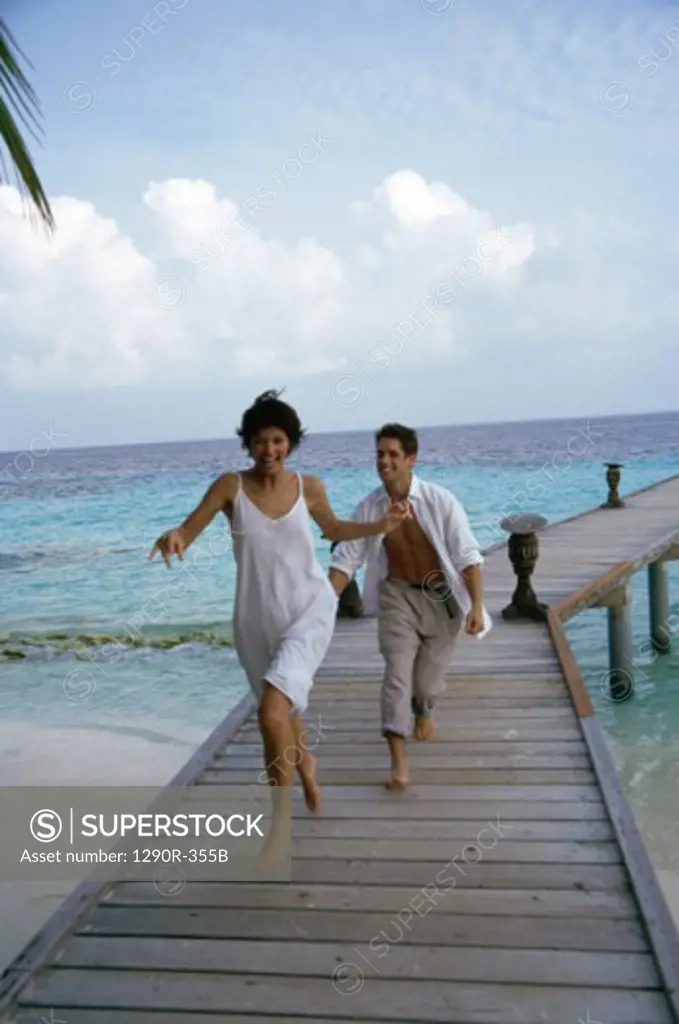 Young couple running on a pier, Maldives