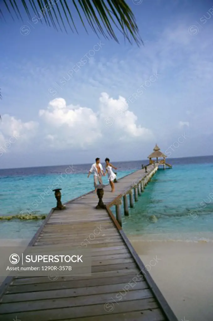 Young couple walking on a pier, Maldives