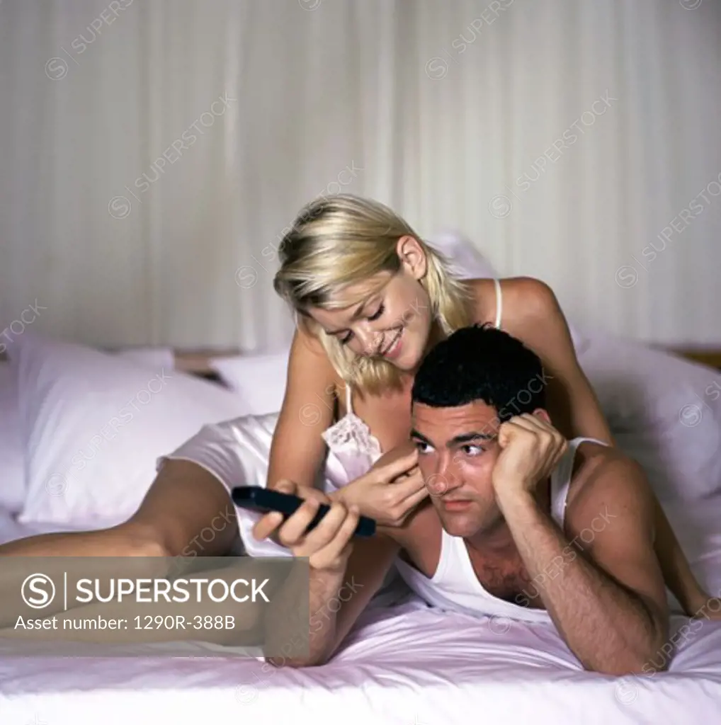 Young couple lying on a bed watching television