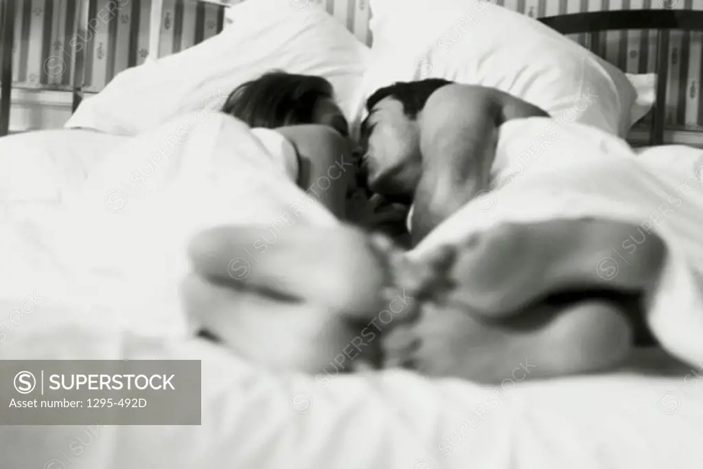 Young couple lying in bed and kissing each other