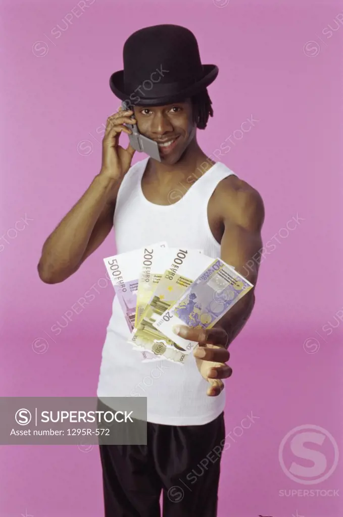 Portrait of a young man talking on a mobile phone holding paper money
