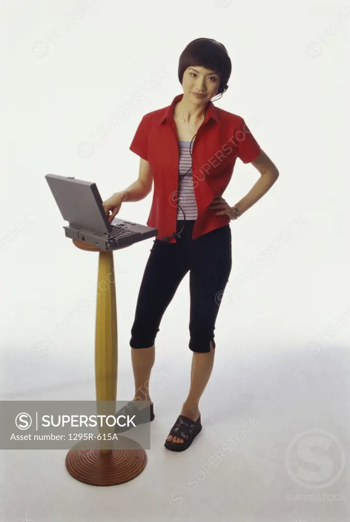 Portrait of a young woman standing in front of a laptop