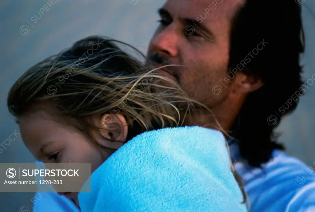 Father holding his daughter in a towel