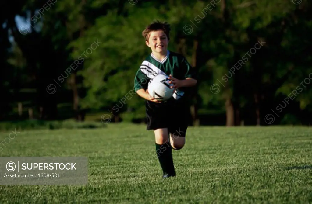 Boy running with a soccer ball in a field