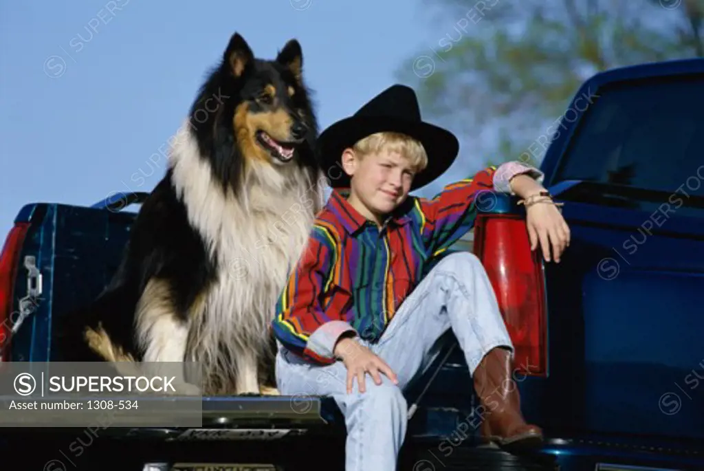 Close-up of a boy sitting with his dog in a pick-up truck