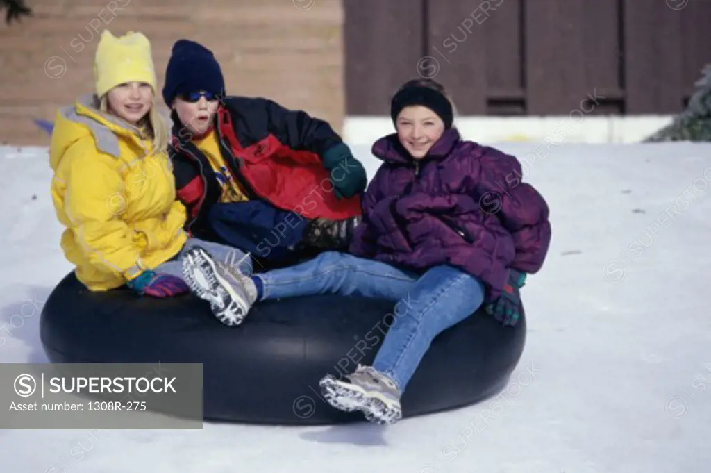 Portrait of two girls and a boy sitting on an inner tube