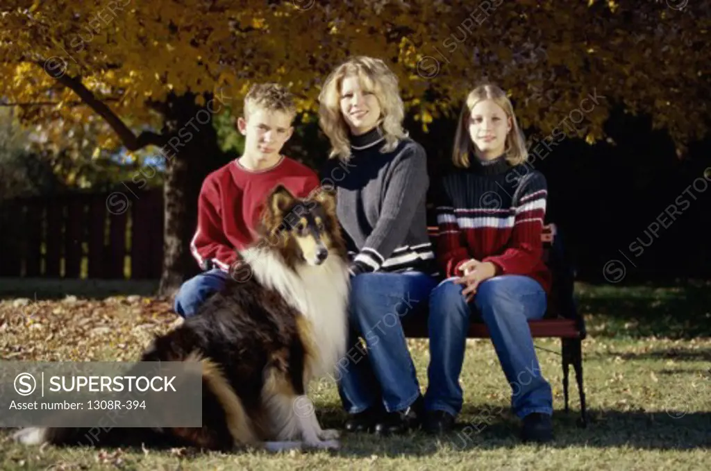 Portrait of a family sitting on a park bench with their dog