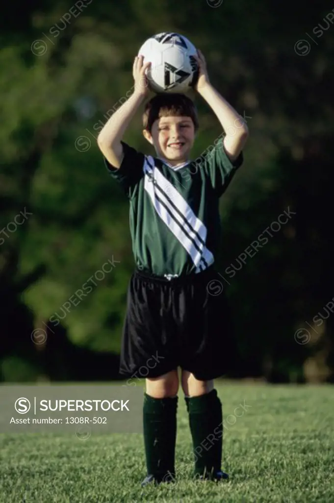 Portrait of a boy holding a soccer ball above his head