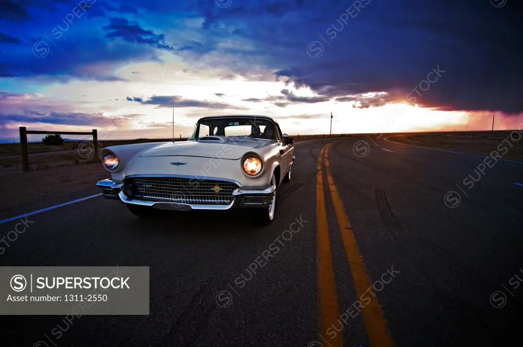 1957 Ford Thunderbird on the road at dusk, Mesa Del Sol, Albuquerque, New Mexico, USA