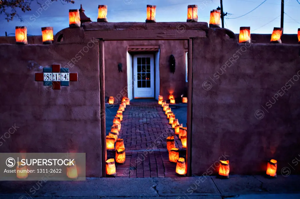 USA, New Mexico, lanterns around house at night, Luminarias, or farolitoes, are found throughout the Southwest. They are made of small paper bags with sand as a weight and a votive candle which is lighted on Christmas Eve