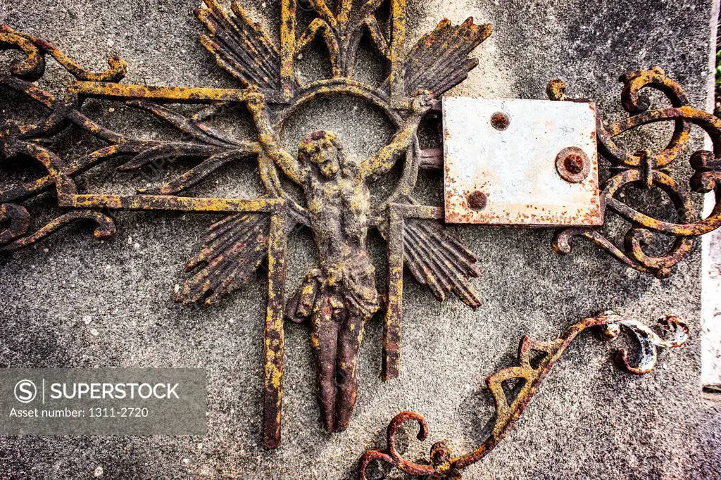 Rusting crucifix with symbol of Jesus found on tombstone.
